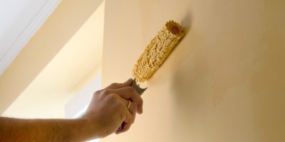 The process of painting the walls in yellow color with a roller latex paint
