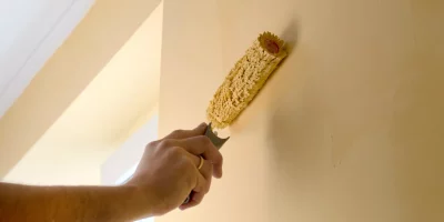 The process of painting the walls in yellow color with a roller latex paint